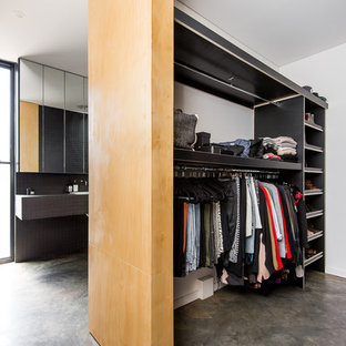 Ispirazione per una piccola cabina armadio unisex moderna con nessun'anta, ante nere e pavimento in cemento