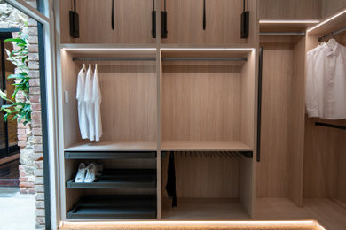 Diseño de armario vestidor actual con armarios abiertos, puertas de armario de madera clara y suelo marrón