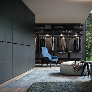 Idee per una cabina armadio unisex minimal di medie dimensioni con ante nere, pavimento in legno massello medio e pavimento marrone