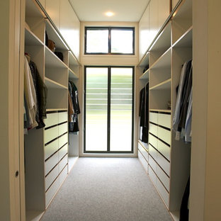 Foto di una cabina armadio unisex design di medie dimensioni con ante bianche, moquette e ante lisce