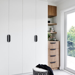 This is an example of a contemporary walk-in wardrobe in Sydney with flat-panel cabinets, white cabinets, carpet and grey floor.