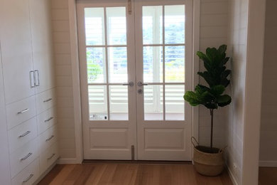 На фото: гардеробная комната среднего размера в современном стиле с плоскими фасадами, белыми фасадами, светлым паркетным полом и бежевым полом для женщин с