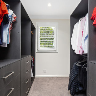 Cette image montre un dressing room avec un placard sans porte, des portes de placard en bois sombre, moquette et un sol rose.
