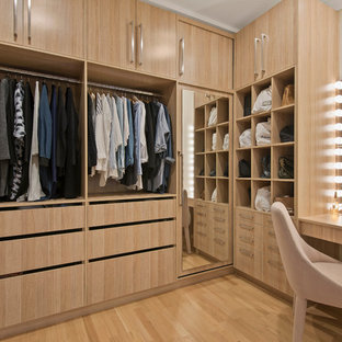 Ispirazione per una cabina armadio unisex design di medie dimensioni con ante in legno chiaro, pavimento in compensato, pavimento beige e ante lisce