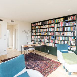 Foto di uno studio minimal con libreria, pareti bianche, parquet chiaro, scrivania autoportante e pavimento beige