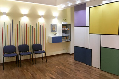 Imagen de despacho actual de tamaño medio con paredes amarillas, suelo laminado y suelo marrón