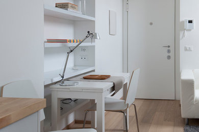 Immagine di un piccolo atelier scandinavo con pareti bianche, pavimento in legno massello medio e scrivania autoportante