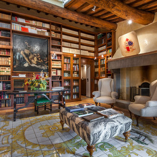 Idee per uno studio tradizionale con libreria, pareti beige, camino classico, cornice del camino in cemento, scrivania autoportante e pavimento multicolore