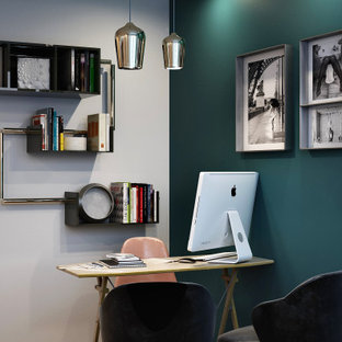 Foto på ett litet hemmabibliotek, med flerfärgade väggar, mörkt trägolv, ett fristående skrivbord och brunt golv