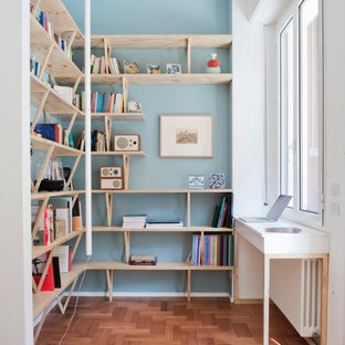 Immagine di uno studio scandinavo di medie dimensioni con pareti blu, pavimento in legno massello medio, libreria, scrivania incassata e pavimento marrone