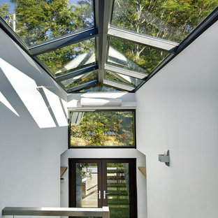 Immagine di una grande veranda moderna con parquet chiaro, camino classico e soffitto in vetro