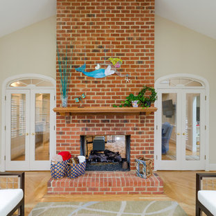 Foto de galería tradicional renovada, de tamaño medio, con suelo de madera en tonos medios, chimenea de doble cara y marco de chimenea de ladrillo