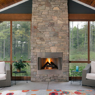 Ejemplo de galería de estilo americano, grande, con marco de chimenea de piedra, suelo de cemento y suelo gris