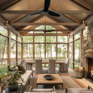 Esempio di una veranda minimal con pavimento in legno massello medio, camino classico, cornice del camino in pietra, soffitto classico e pavimento marrone