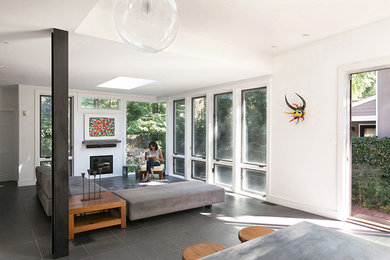 Foto di una veranda con camino classico, cornice del camino in metallo, lucernario e pavimento grigio