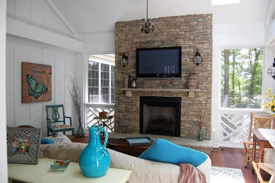 Inspiration pour une grande véranda chalet avec un sol en bois brun, une cheminée standard, un manteau de cheminée en pierre, un plafond standard et un sol marron.