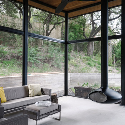 Large minimalist concrete floor and gray floor sunroom photo in Austin with a hanging fireplace, a metal fireplace and a standard ceiling