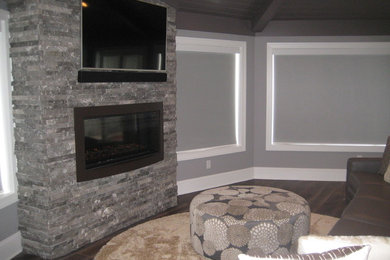 グランドラピッズにある広いラスティックスタイルのおしゃれなサンルーム (濃色無垢フローリング、石材の暖炉まわり、標準型天井、コーナー設置型暖炉) の写真