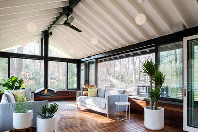 Exemple d'une véranda rétro avec cheminée suspendue, un plafond standard et un sol en bois brun.