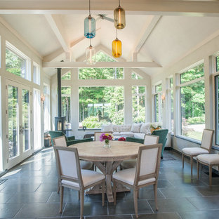 Immagine di una grande veranda country con pavimento in gres porcellanato, cornice del camino in metallo, soffitto classico, pavimento grigio e stufa a legna