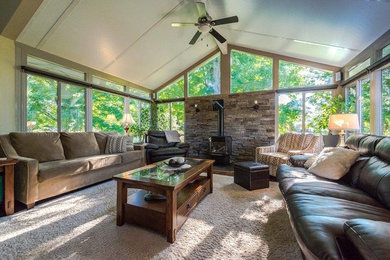 Large classic conservatory in Toronto with carpet, a wood burning stove, a stone fireplace surround, a standard ceiling and beige floors.