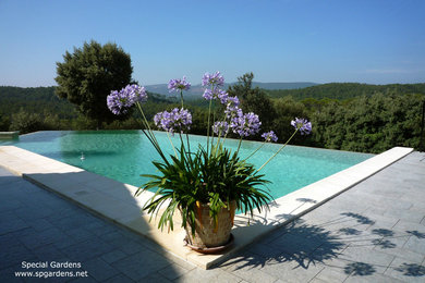 This is an example of a large mediterranean custom shaped infinity swimming pool in Nice with tiled flooring.