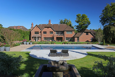 Large traditional back rectangular swimming pool in Surrey with tiled flooring.
