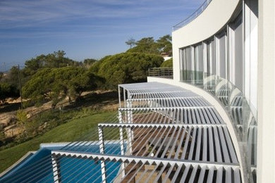 Photo of a large modern back custom shaped infinity swimming pool in Other with a water feature and decking.