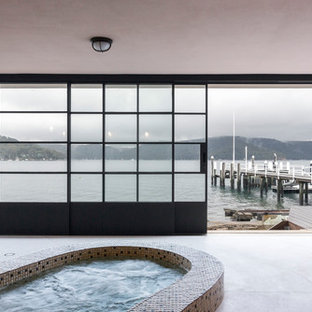 Contemporary indoor pool in Sydney with a hot tub.