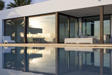 Diseño de casa de la piscina y piscina alargada actual grande rectangular en patio trasero