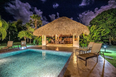 Foto de casa de la piscina y piscina alargada tropical grande rectangular en patio trasero con adoquines de piedra natural