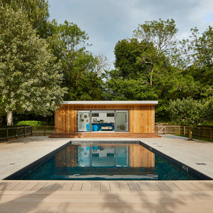 Contemporary back rectangular swimming pool in Essex with a pool house and decking.