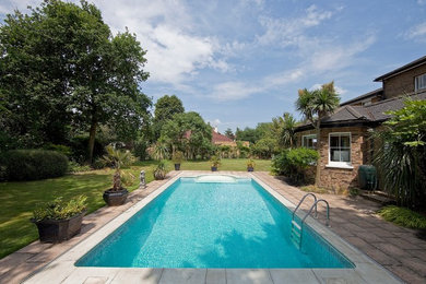 Foto de piscina alargada tradicional grande rectangular en patio lateral con adoquines de hormigón