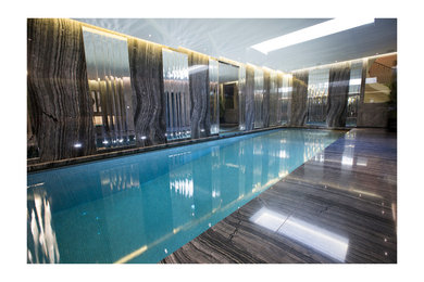 Design ideas for a large contemporary indoor rectangular swimming pool in London with a water feature.