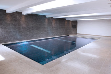 This is an example of a large contemporary indoor rectangular swimming pool in London with a water feature.