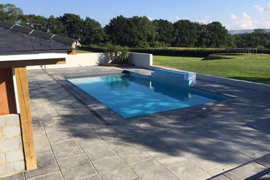 Design ideas for a large contemporary back hot tub in Sussex with natural stone paving.