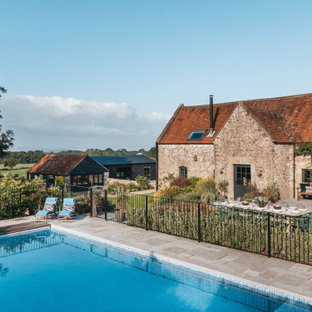 Large rural back rectangular swimming pool in Other with natural stone paving.