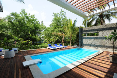 Pool - large tropical backyard rectangular pool idea in Other