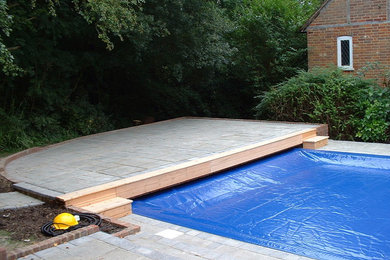 Photo of a medium sized classic side custom shaped lengths swimming pool in Hampshire with natural stone paving.