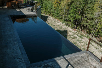 Example of a minimalist concrete and rectangular infinity pool design in Other