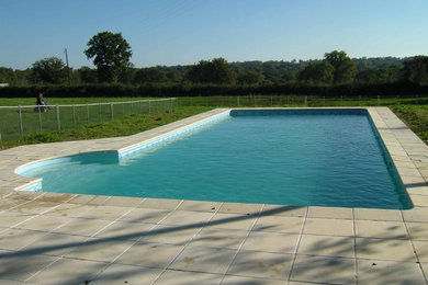Medium sized contemporary back rectangular lengths swimming pool in Wiltshire with natural stone paving.