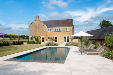 Medium sized farmhouse back rectangular swimming pool in Gloucestershire with concrete slabs.