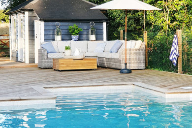 Ejemplo de piscina de estilo de casa de campo grande rectangular en patio trasero con entablado
