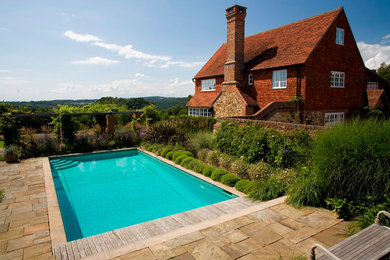 Esempio di una piscina naturale tradizionale rettangolare di medie dimensioni e dietro casa con pavimentazioni in pietra naturale