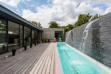 ロンドンにあるコンテンポラリースタイルのおしゃれな競泳用プール (デッキ材舗装、噴水) の写真