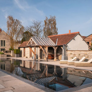 This is an example of a large farmhouse back rectangular swimming pool in Cornwall with a hot tub.