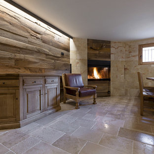 Cette image montre un grand sous-sol minimaliste donnant sur l'extérieur avec un mur marron, un sol en calcaire, une cheminée d'angle, un manteau de cheminée en bois et un sol beige.