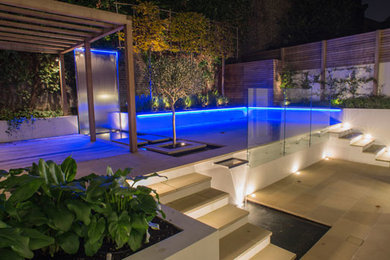 Photo of a small contemporary back terrace in London with a water feature and a pergola.