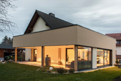 Exemple d'une grande terrasse arrière tendance avec une extension de toiture.
