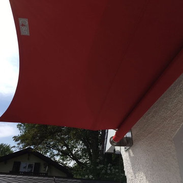 Ein rotes Sonnensegel für eine weiße Landhaus-Villa am Chiemsee